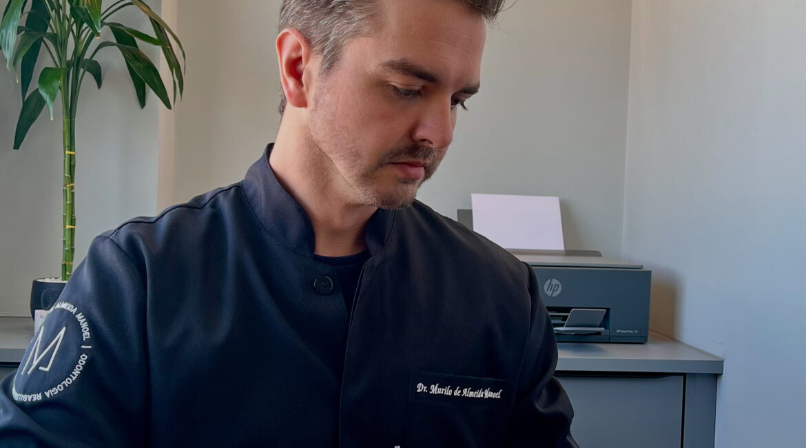 Dr. Murilo de Almeida Manoel, dentista especialista em Botucatu, analisando planejamento clínico e artigos científicos de odontologia.